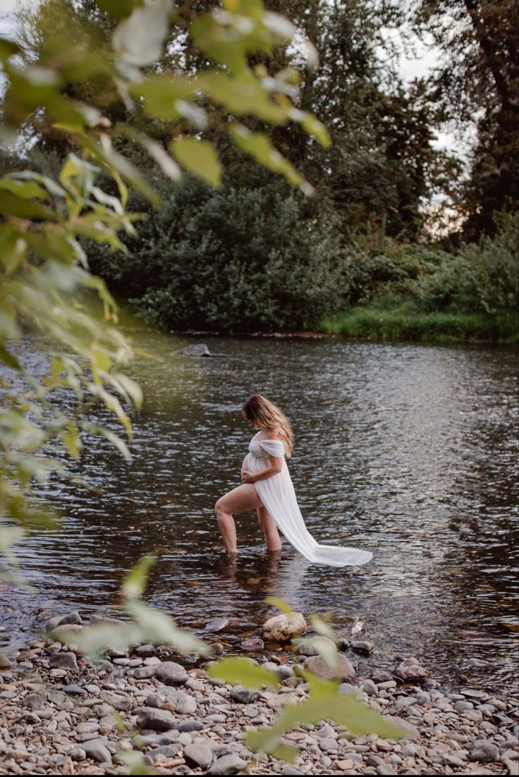 a woman is standing in the water with her dress flowing over her head and body