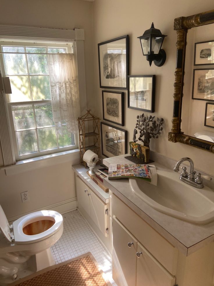 a bathroom with a toilet, sink and pictures hanging on the wall next to it