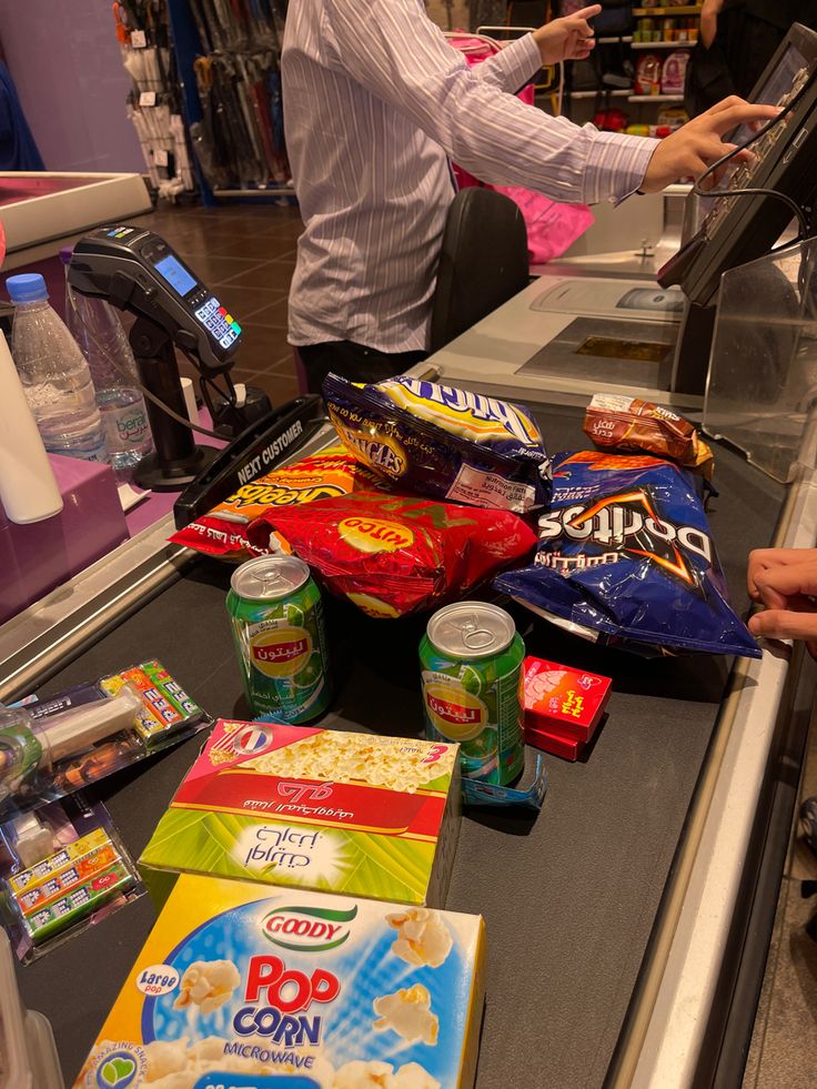 a man standing at a cash register in a grocery store next to snacks and drinks