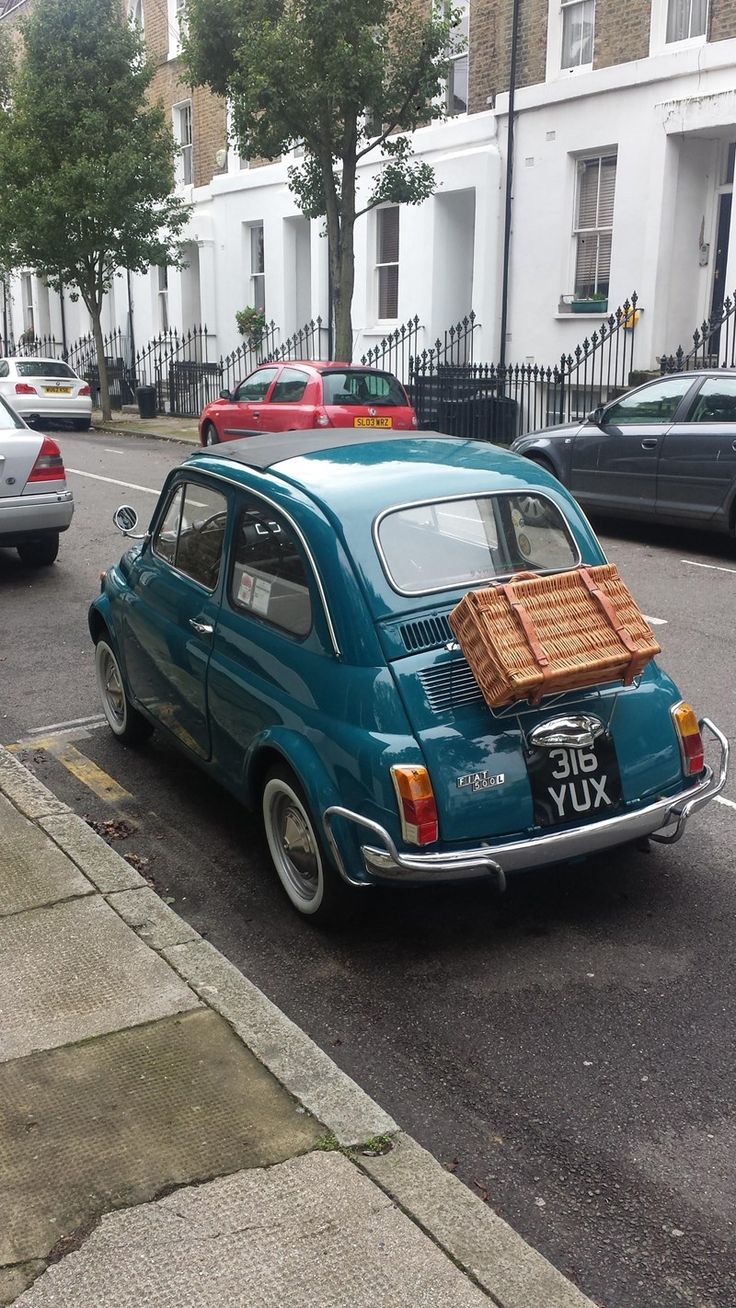 an old car is parked on the side of the street with luggage strapped to it's back