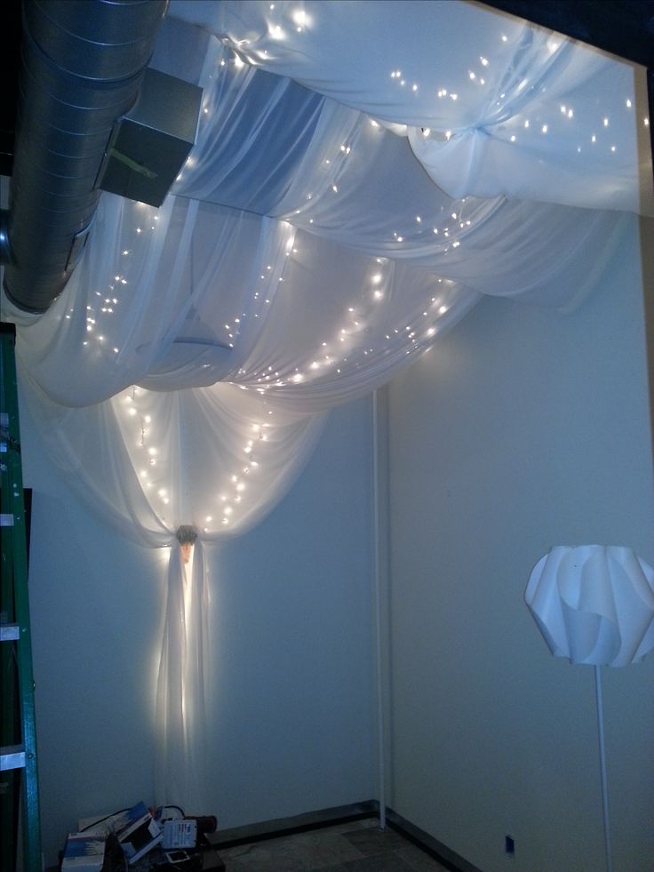 a room with white curtains and lights on the ceiling