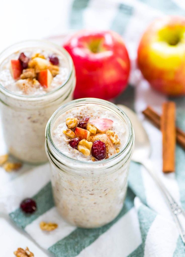 two jars filled with oatmeal and fruit on top of a striped cloth