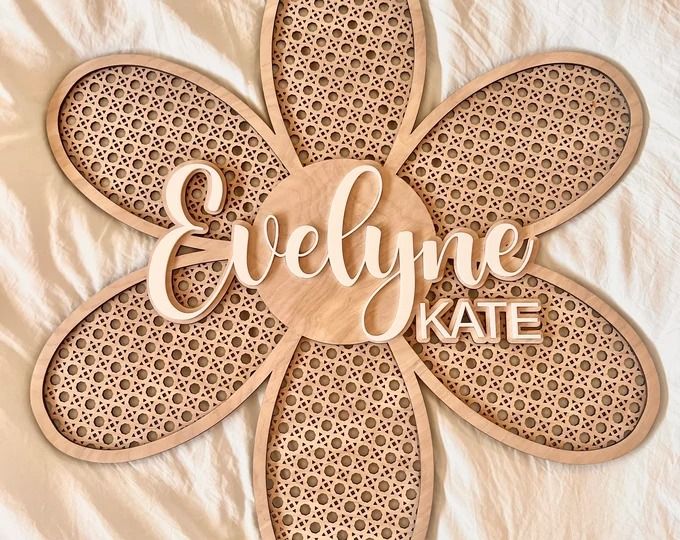 a wooden sign that says evelyne kate on top of a white sheet with an intricate flower