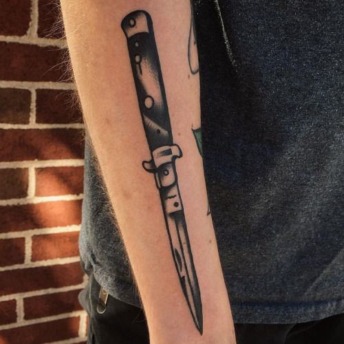 a man's arm with a knife tattoo on the left side of his arm