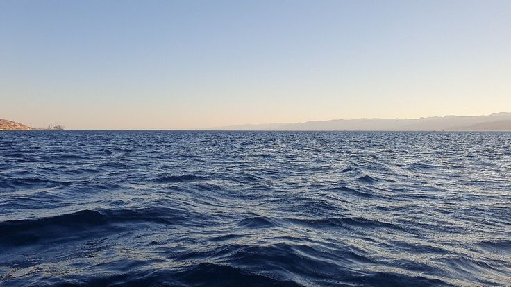 the water is very blue and there are mountains in the distance on the far side