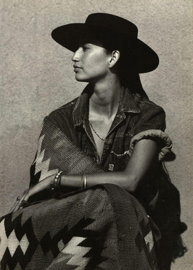 an old photo of a woman wearing a black hat and sitting on a chair with a blanket