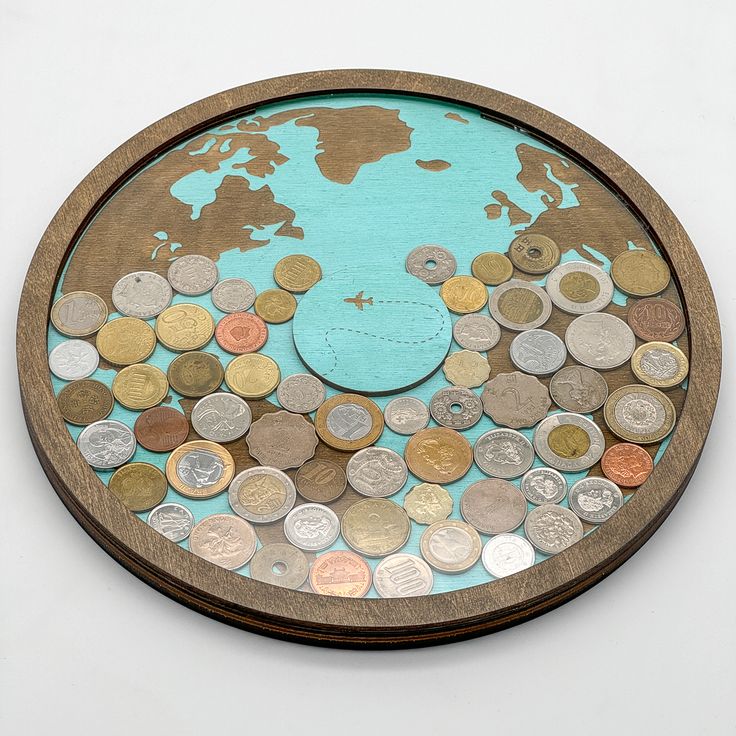 a wooden plate filled with lots of different types of coins on top of a white surface