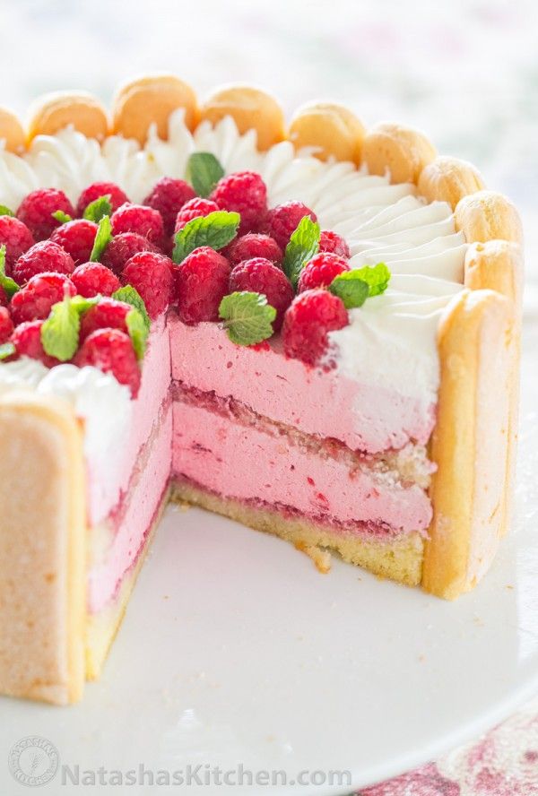 a cake with raspberries on top is cut in half and ready to be eaten