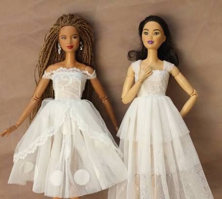 two dolls dressed in white dresses standing next to each other