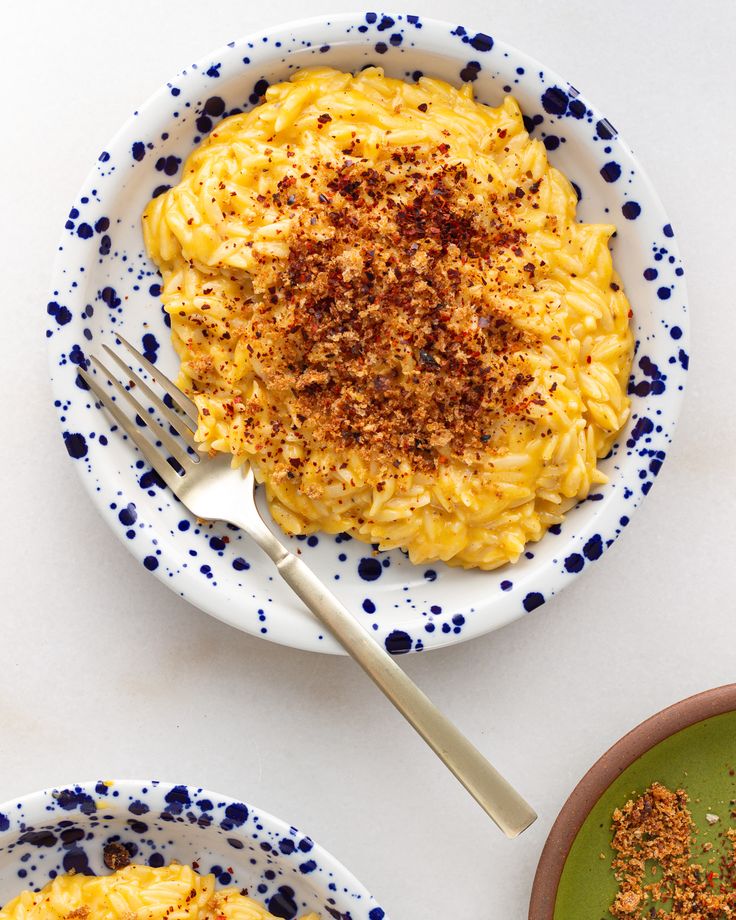 two bowls filled with macaroni and cheese on top of a white tablecloth