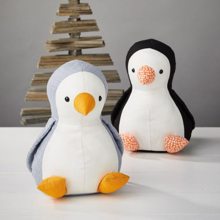 two stuffed penguins sitting next to each other in front of a christmas tree with the words amici penguin on it