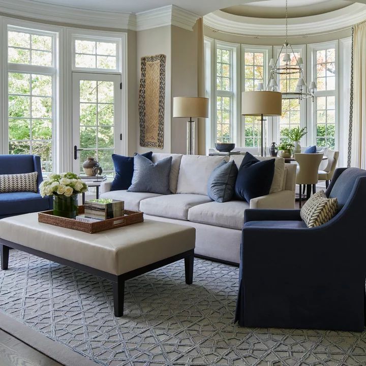 a living room filled with lots of furniture and large windows in the wall behind it