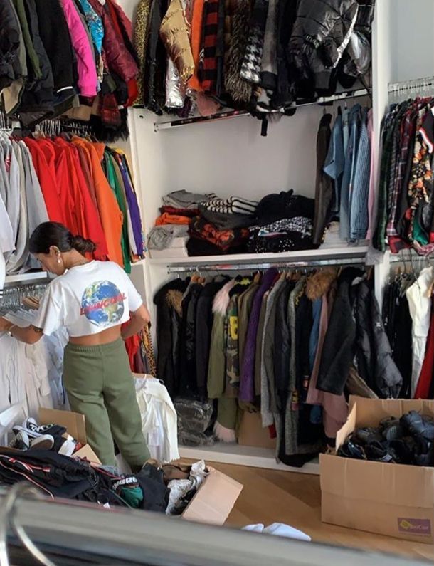 a woman standing in front of a closet filled with clothes