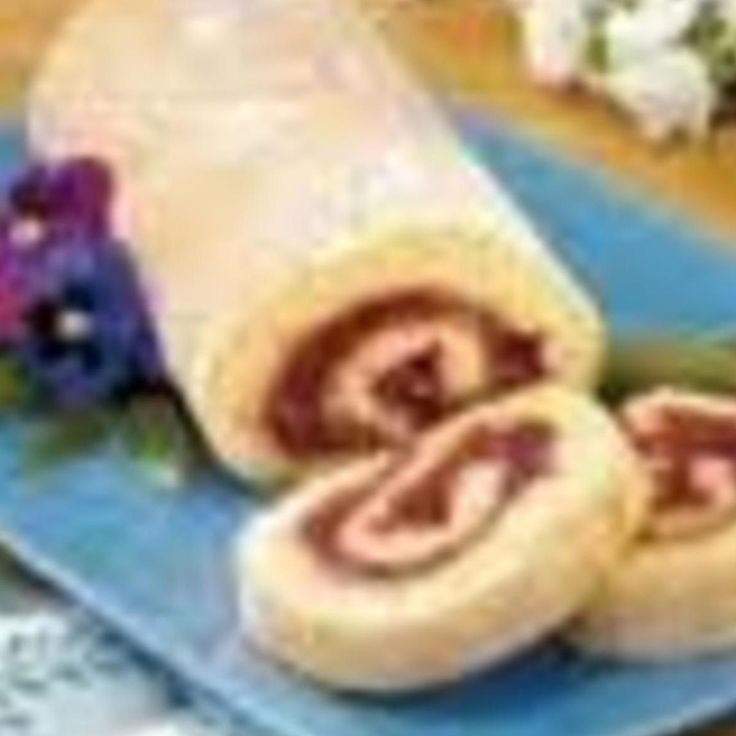 a blue plate topped with sliced up food on top of a wooden table next to flowers