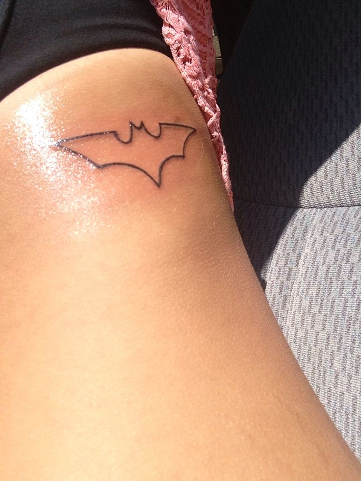 a small tattoo on the back of a woman's thigh, depicting a bat