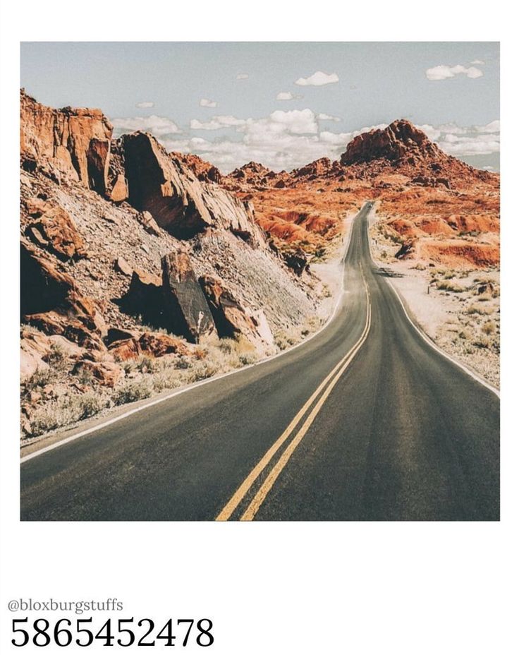 an empty road in the desert with mountains and rocks behind it on a sunny day