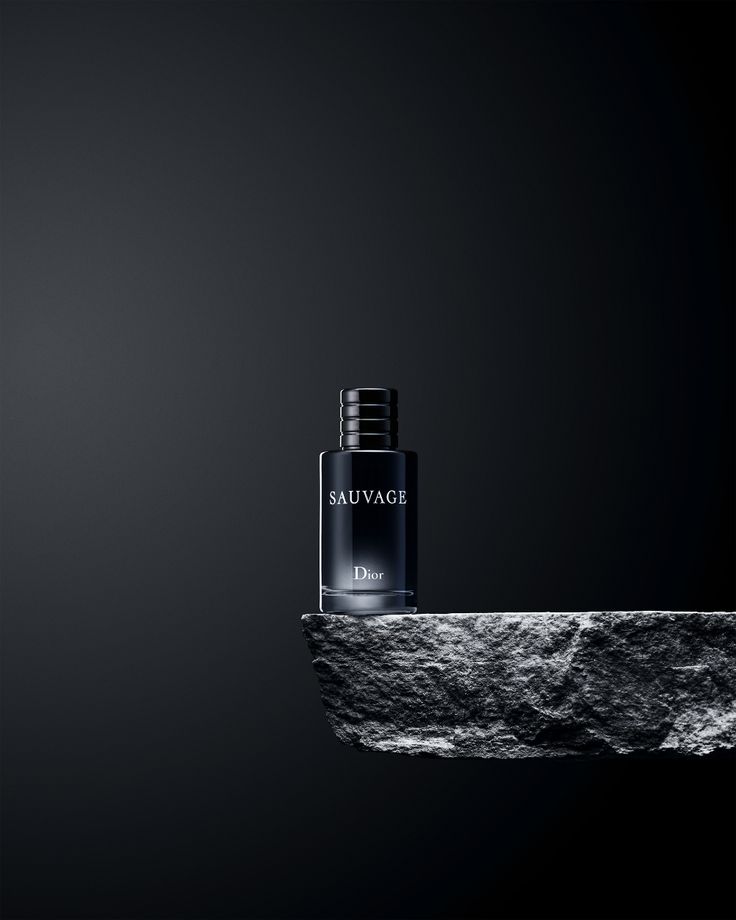 a bottle of perfume sitting on top of a rock in front of a black background