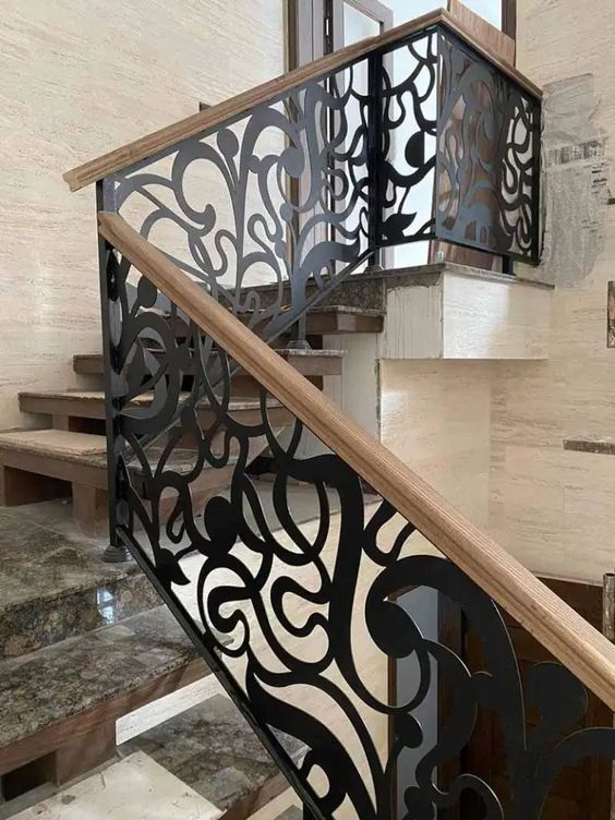 an iron stair railing with wooden handrails