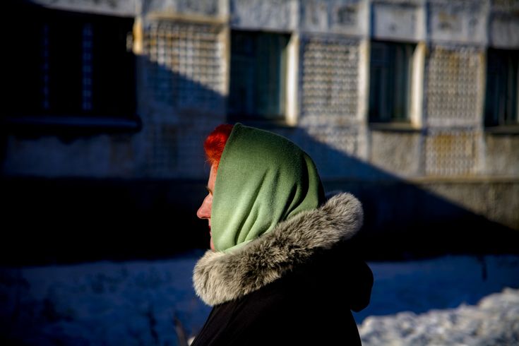 a woman wearing a green and red scarf on her head in front of a building