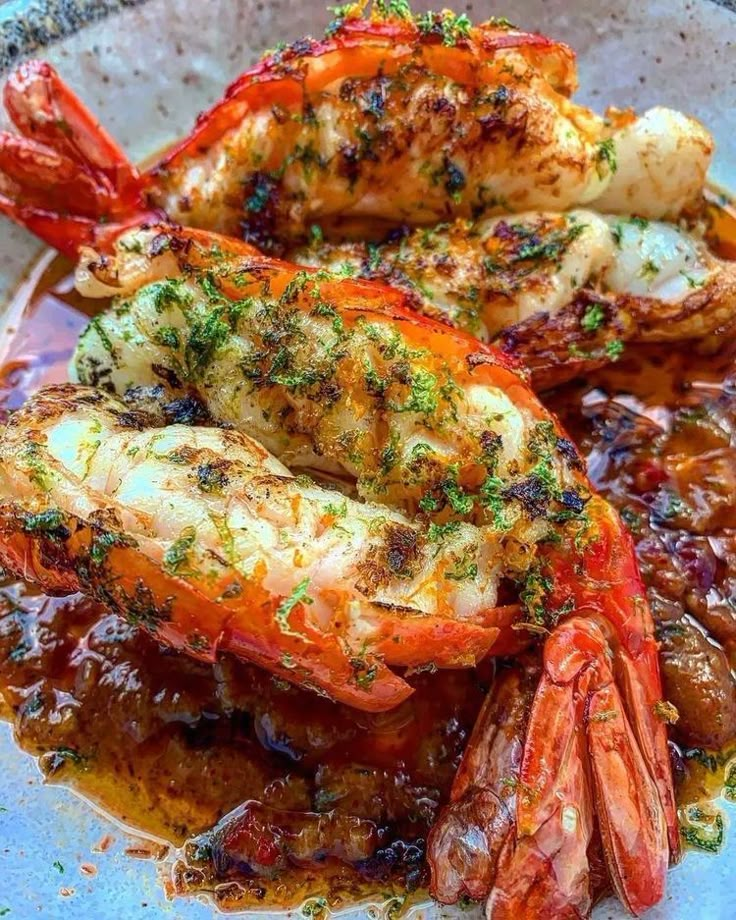 cooked lobsters with sauce and herbs on a plate