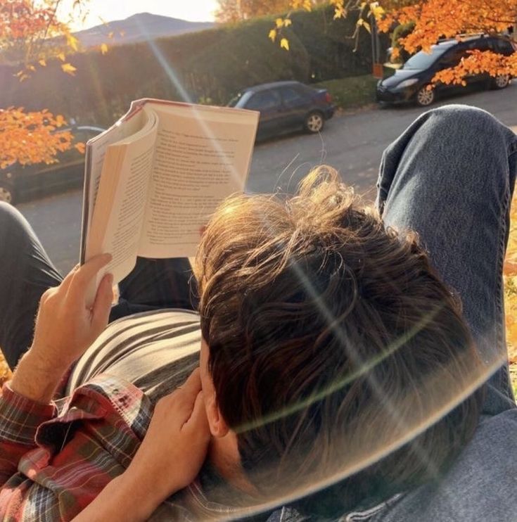 a man laying on the ground reading a book