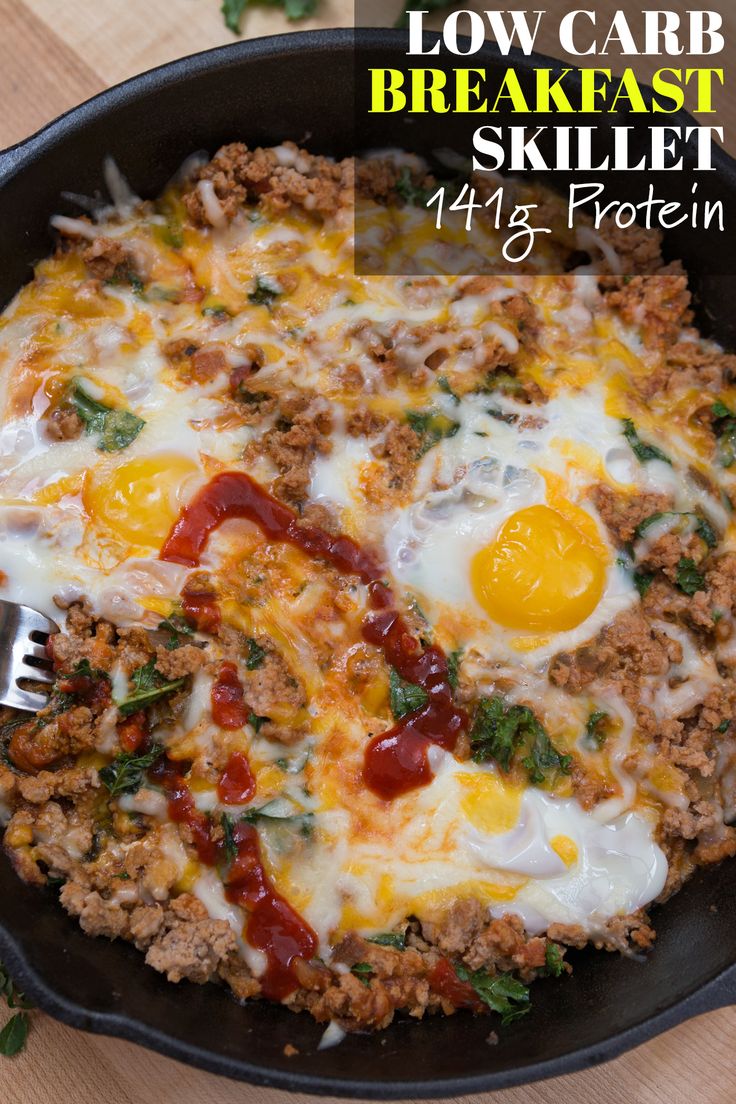 a skillet filled with eggs and meat on top of a wooden table next to vegetables