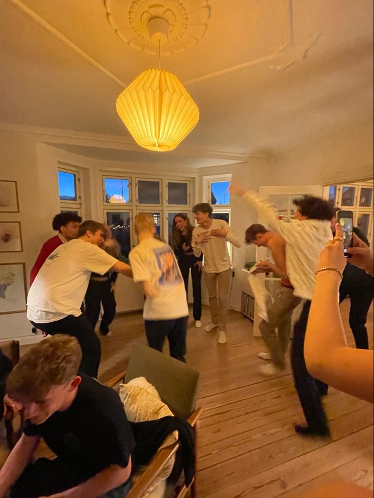 a group of people standing in a living room with one person holding a cell phone