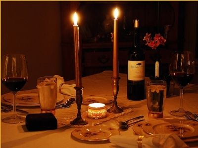 black and white photograph of table setting with wine glasses, candles, plates and utensils