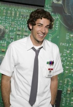 a man wearing a white shirt and tie standing in front of a computer circuit board