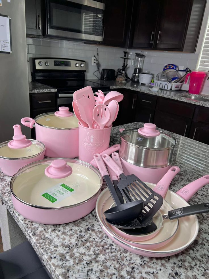 the kitchen counter is covered in pink pots and pans with utensils on them