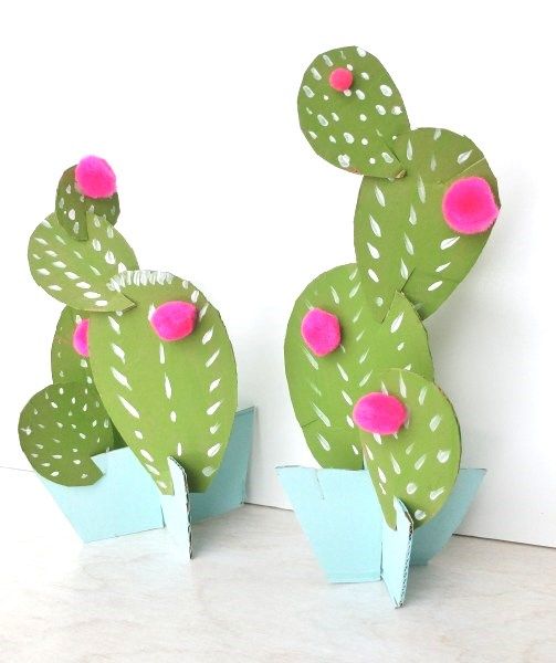 two green and pink cactus sculptures sitting on top of each other in front of a white wall