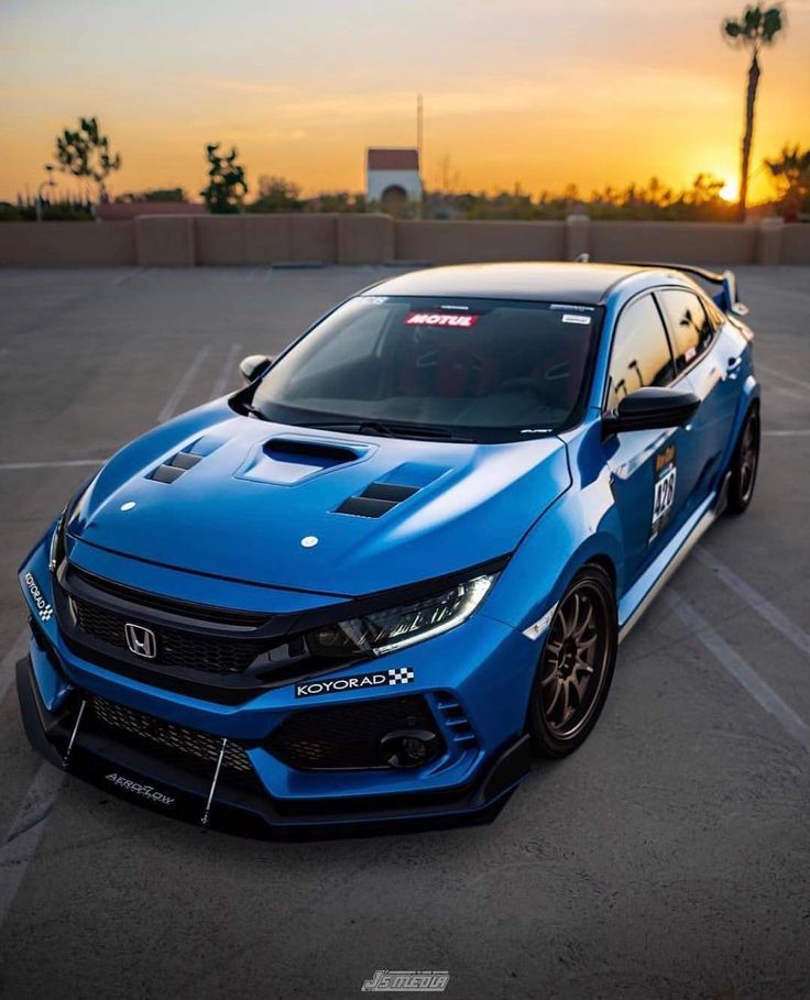 a blue car parked in a parking lot with the sun setting on it's side