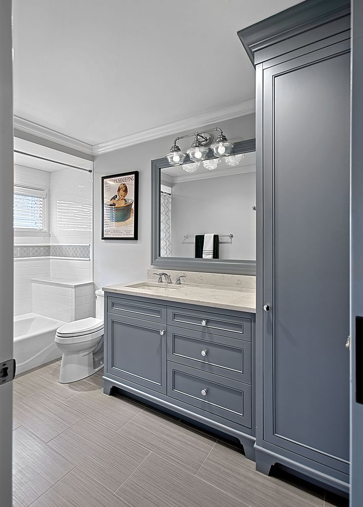 a bathroom with gray cabinets and a white toilet