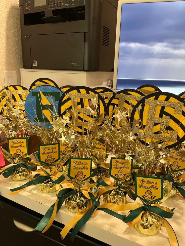 some gold and green decorations are on a desk next to a laptop computer with the ocean in the background