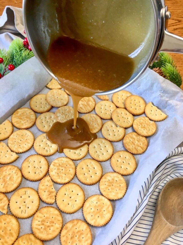 a person pouring caramel sauce on crackers