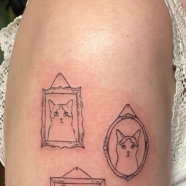 a woman's thigh with three different tattoos on her legs and one has a cat in the mirror