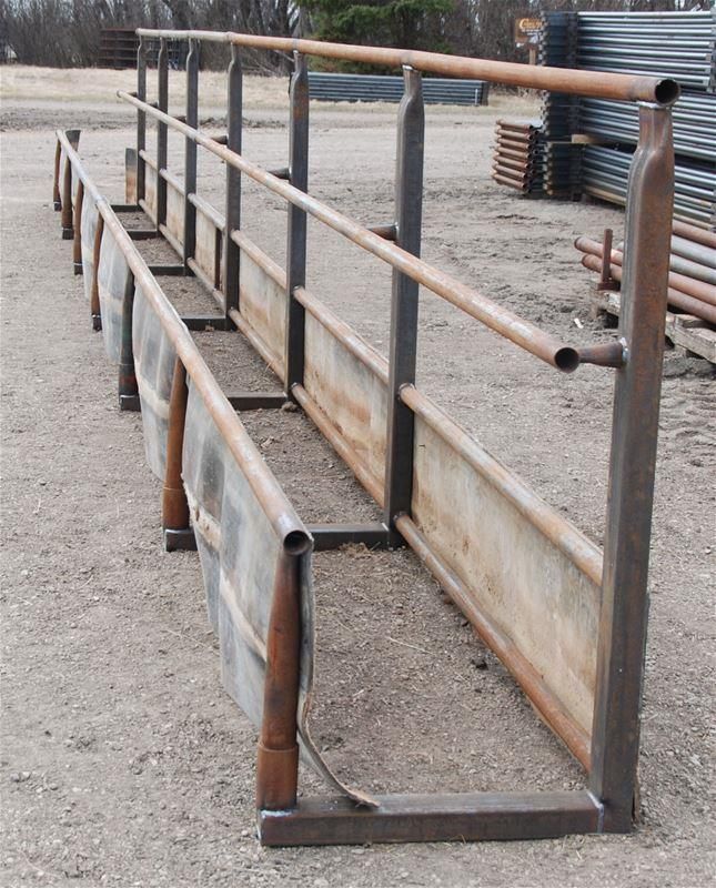 a row of wooden benches sitting on top of a dirt field next to a metal fence