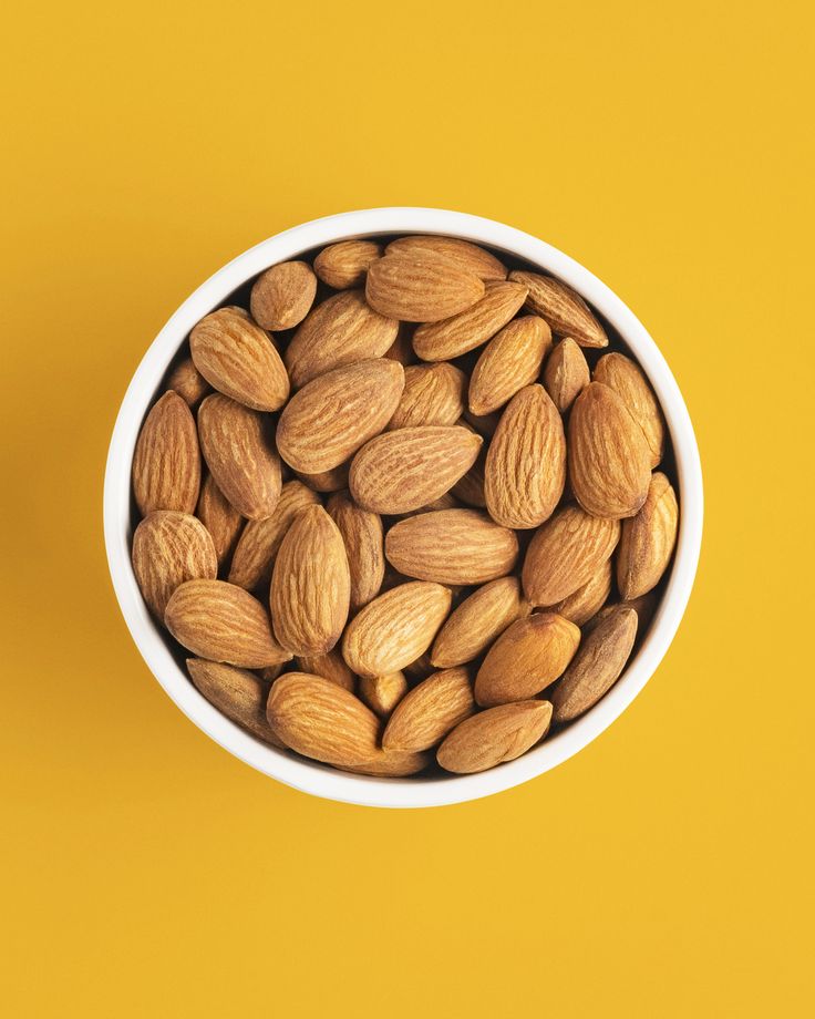 almonds in a white bowl on an orange background