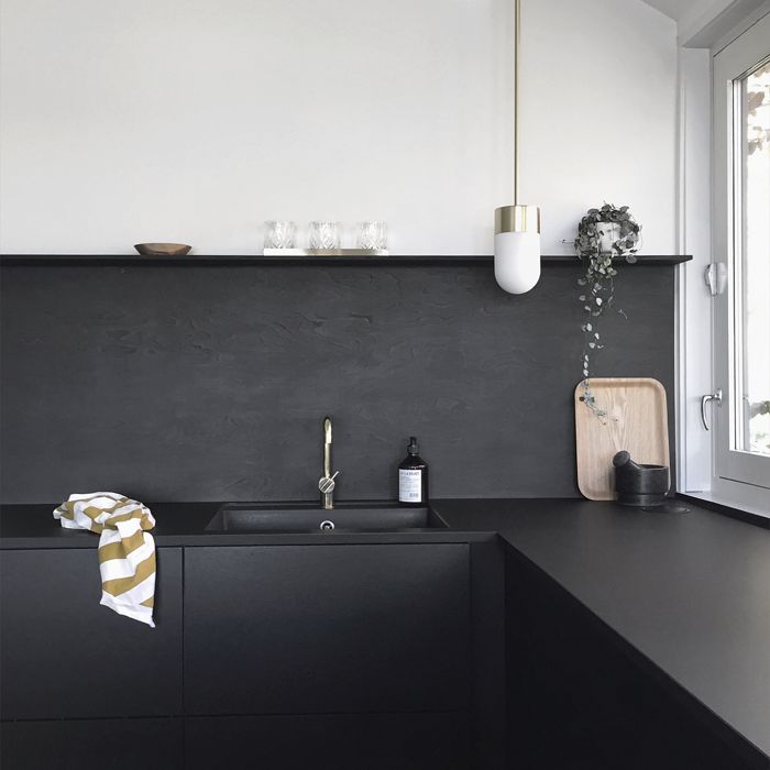 a kitchen with black counter tops and white walls, along with a sink in the center