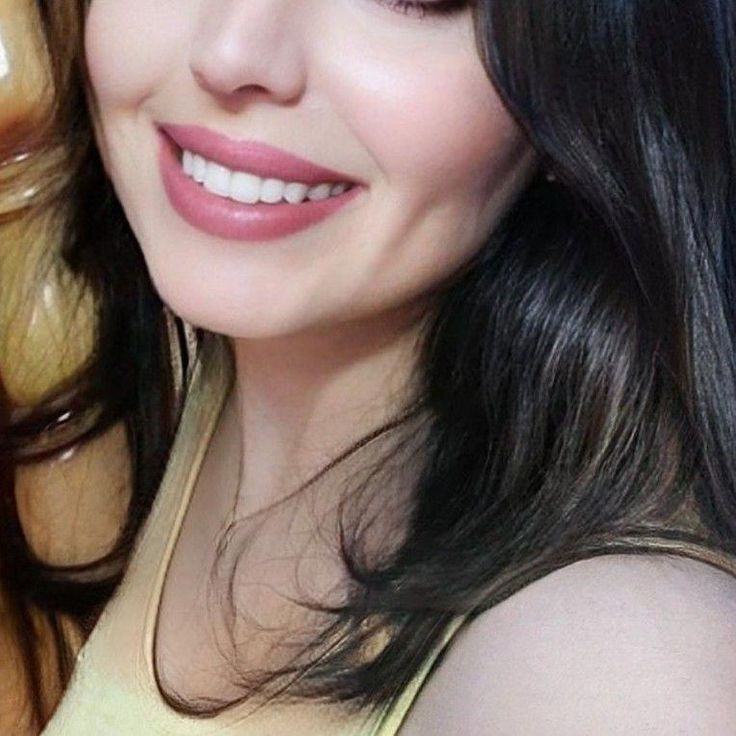 a close up of a woman with long black hair and wearing a yellow tank top