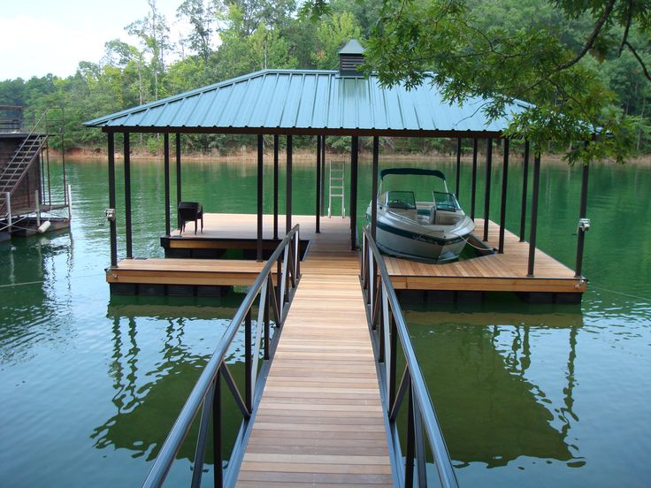 a boat is docked at the end of a wooden dock with a metal roof over it