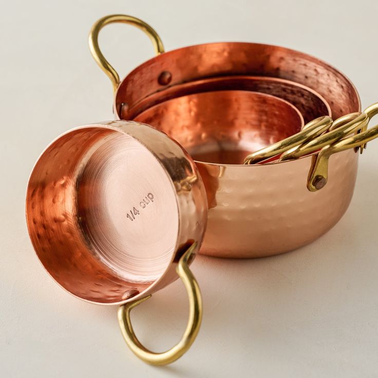 two copper pans sitting next to each other