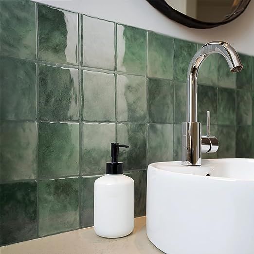 a bathroom sink with soap dispenser and green tiles on the wall behind it