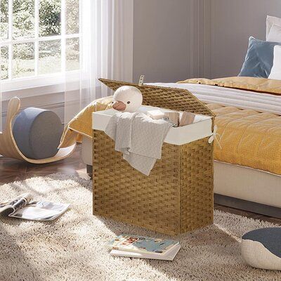 a wicker basket on the floor in front of a bed with pillows and blankets