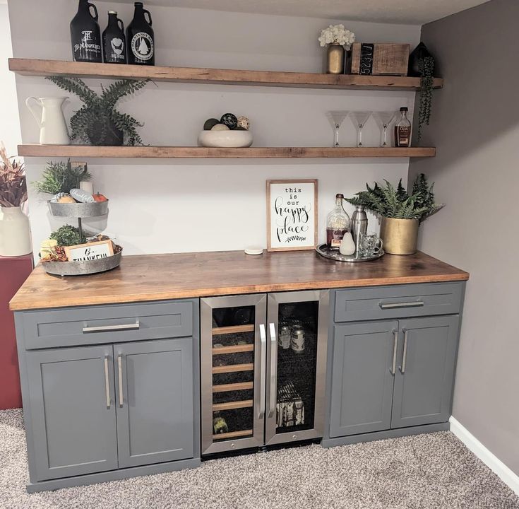 a kitchen with grey cabinets and shelves filled with wine