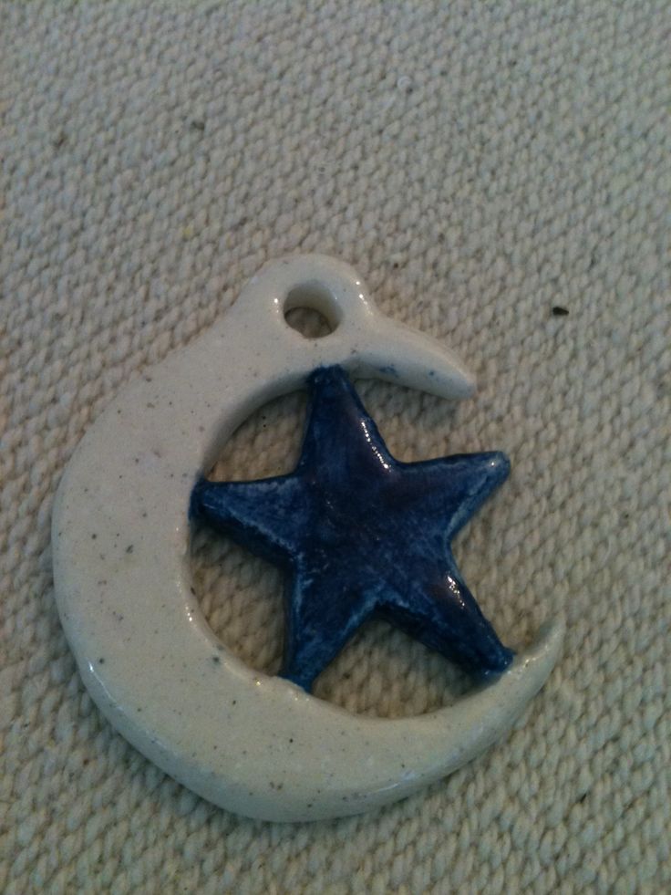 a ceramic ornament with a blue star and moon hanging from it's side