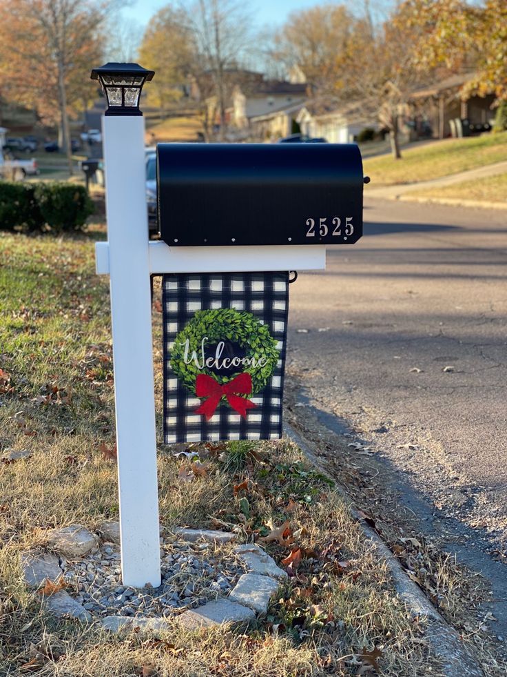 a mailbox with a christmas wreath on it is next to a street and trees