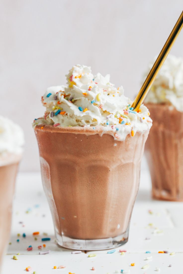 two glasses filled with ice cream and sprinkles on top of a table