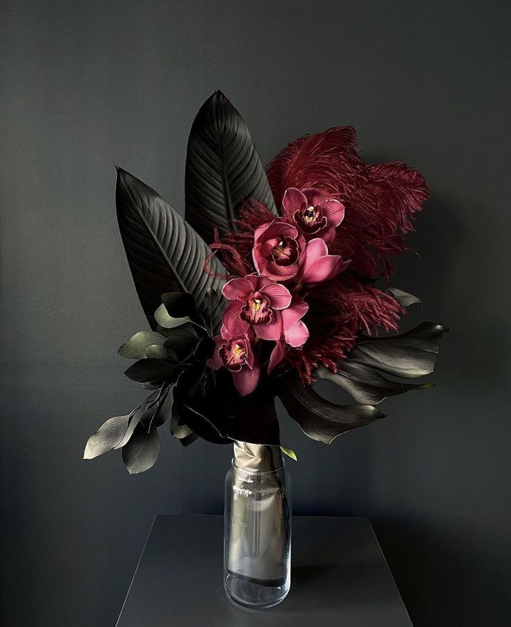 a vase filled with lots of flowers on top of a table next to a wall