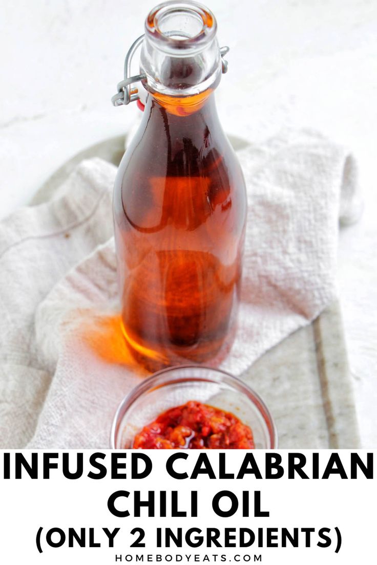 a glass bottle filled with chili oil next to a small bowl full of hot sauce